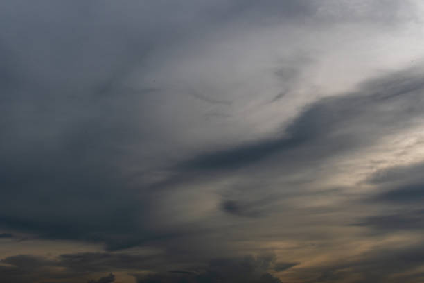 The sky is cloudy and the sun is setting. The clouds are dark and the sky is a deep blue