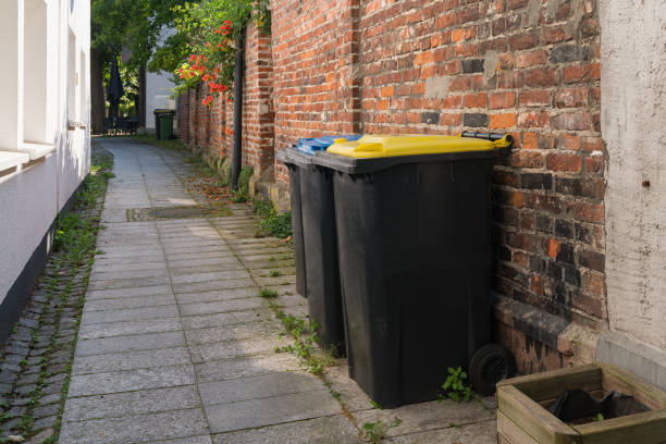 istock Plastic trash bins lined up against a brick wall on a narrow street 2170052609
