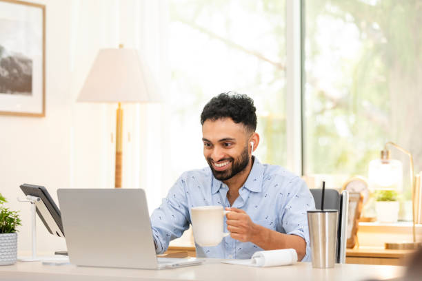 istock Young man enjoys cup of coffee while attending online class 2170054044