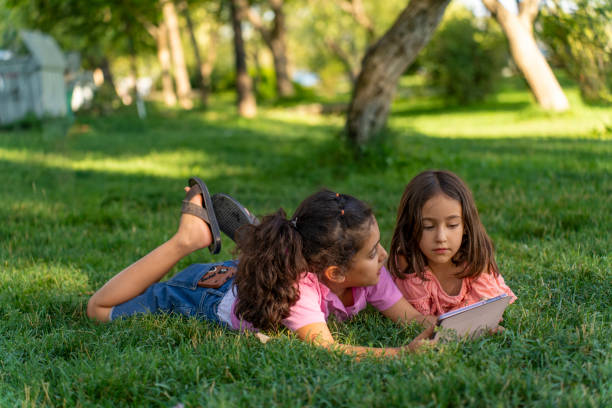 istock Girls lying on the grass using a tablet. 2170055639