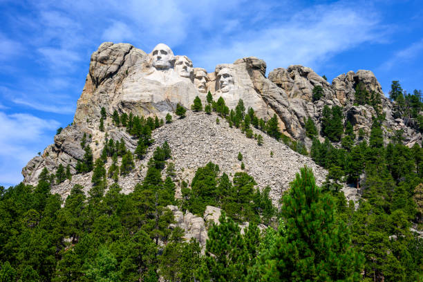 Mt. Rushmore_5 The faces of George Washington, Thomas Jefferson, Theodore Roosevelt and Abraham Lincoln are sculpted into a mountain at Mount Rushmore. Three million tourists visit Mount Rushmore annually. This image was taken in the summer with bright blue skies visible above the mountain. theodore roosevelt us president stock pictures, royalty-free photos & images