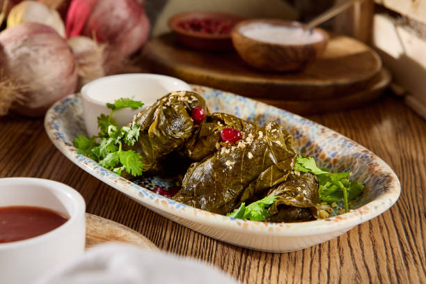 istock Dolma Wrapped in Grape Leaves with Garnish and Sauces on a Rustic Table 2170057779