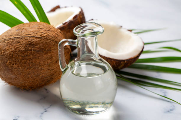 Bottle of coconut oil and fresh coconuts with palm leaf