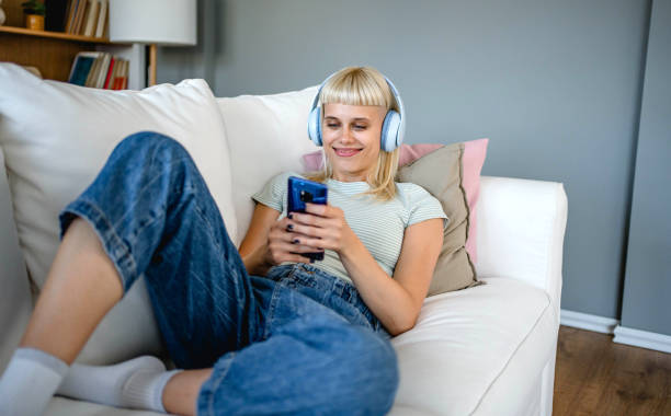 istock Young woman using phone while relaxing at home 2170058843