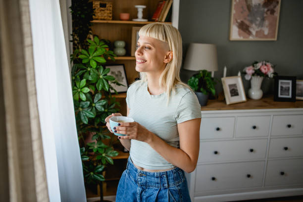 istock Woman with coffee looking through the window 2170059262