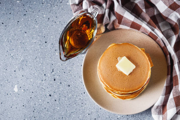 fresh tasty pancakes with maple syrup on a light stone background.