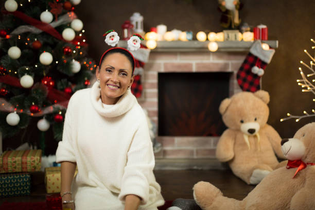 A woman in front of a fireplace with a Christmas decoration