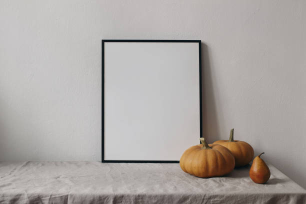 istock Autumn still life. Vertical thin black picture frame mockup. Orange pumpkins, pear fruit on linen table cloth. White wall background. Minimal rustic interior, neutral color. Halloween, Thanksgiving 2170063918