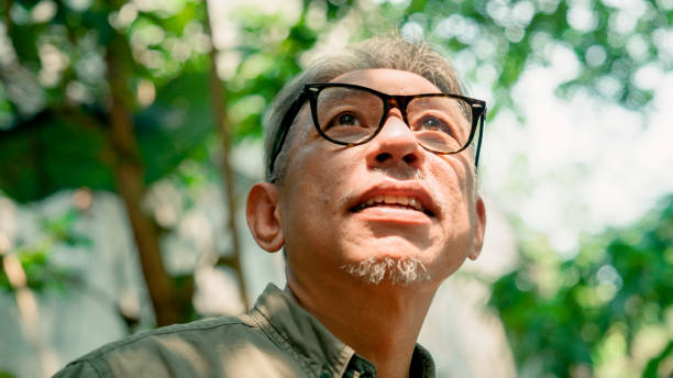 Retired Asian man looking around the nature-themed cafe while talking with old friends.