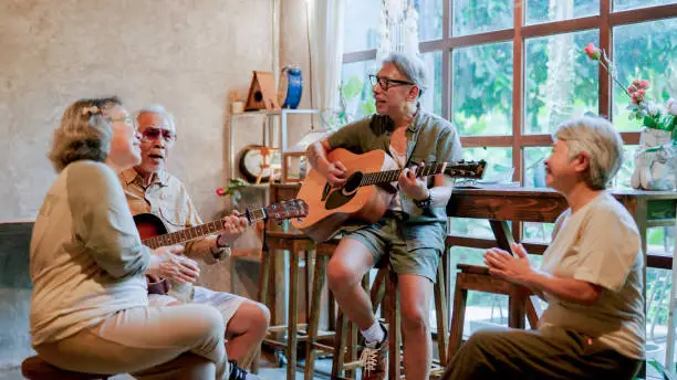 Elderly Asian friends playing music together at home on weekend.