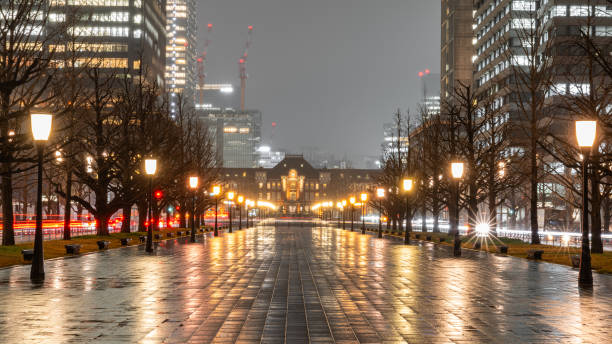 In Chiyoda, Japan, we captured this iconic train station in a beautiful nighttime composition.  The rows of streetlamps and trees lead us down a rainy, brick path until our eyes meet the magnificent frontage of Tokyo Station.  Surrounding the scene is lively, long-exposure traffic and large, mysterious skyscrapers showcasing the modern city life of Tokyo.  The beautiful pedestrian-only brick path has a wonderful illumination on this rainy night, as it perfectly reflects the colorful lamplights.