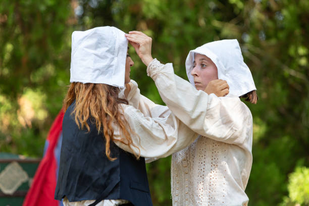 Two women are adjusting their white bonnets, getting ready to portray life in the 16th century