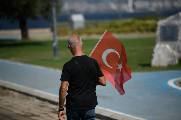 Izmir, Turkey - August 30 2024: A man walking while holding a Turkish flag during the Victory Day celebrations, showcasing national pride and unity
