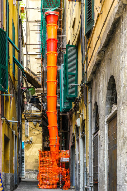 Orange collapsible plastic construction debris pipe at the renovation construction site of an old building in a narrow street of an old Italian city