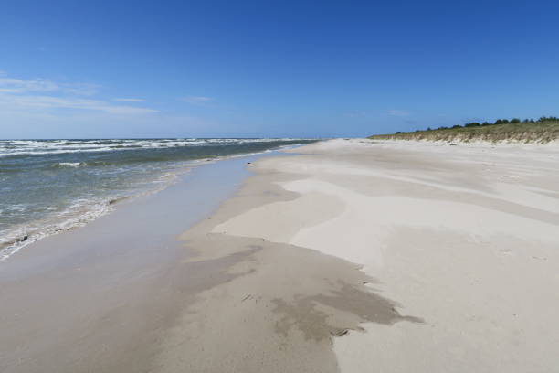 There is nobody on this part of Sandhammaren beach in Ystad on this sunny but windy summers day. Waves are breaking on the sand of the beach in the Swedish province Scania.