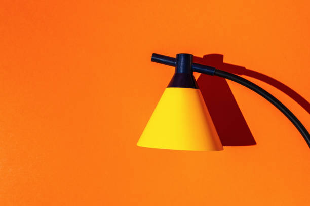 Vibrant Yellow Modern Desk Lamp Against Bright Orange Background