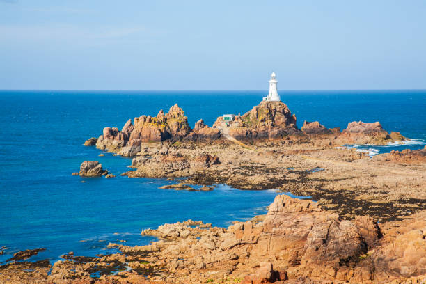Jersey coastline at sunset with lighthouse and rocks