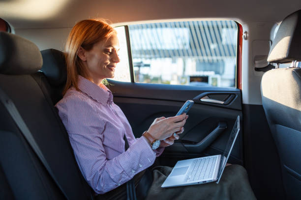 istock Businesswoman using phone and laptop in car during commute 2170084877