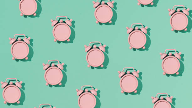 istock Vintage pink alarm clock, pattern on a mint green background. 2170088325