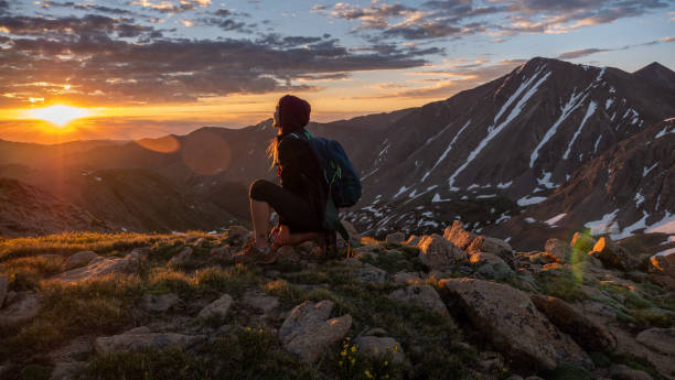 A girl sits on a mountain at sunrise