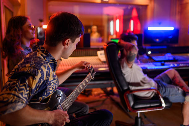 Diverse band member playing guitar while recording song in a music studio