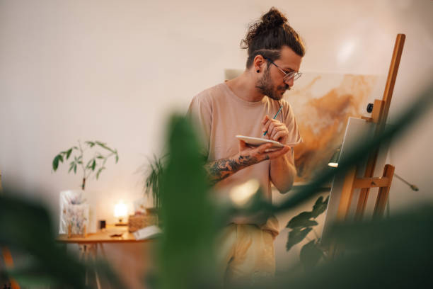 istock Focused trendy painter painting on easel at creative art studio. 2170094034