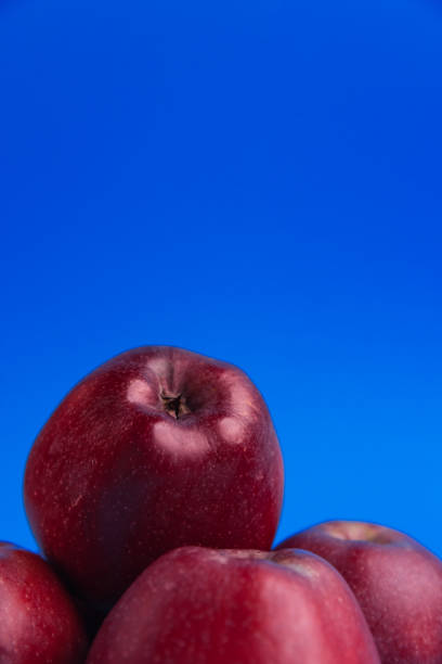 A group of red apples is showcased against a vibrant blue background. Perfect for themes related to fruit, freshness, and bold color contrasts.