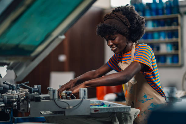 istock Happy diverse graphic worker pressing ink with squeegee at printing shop 2170097484