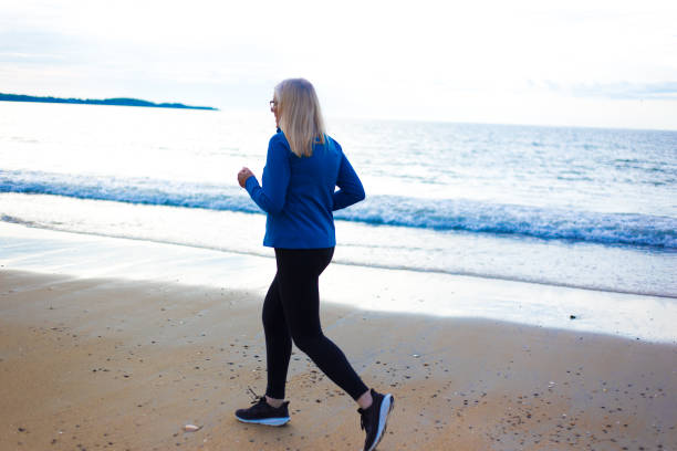 istock Active Senior Woman Jogging on Beach 2170097616