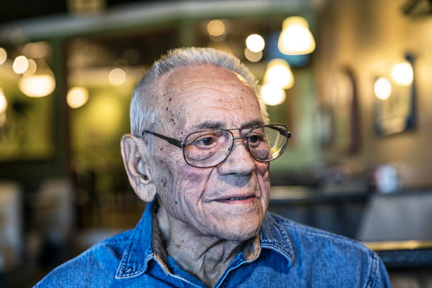 During a day visit to the lake resort, Grandpa is sitting in a restaurant with his family listening to the discussion around the table. He is wearing one of his favorite denim button down shirts.