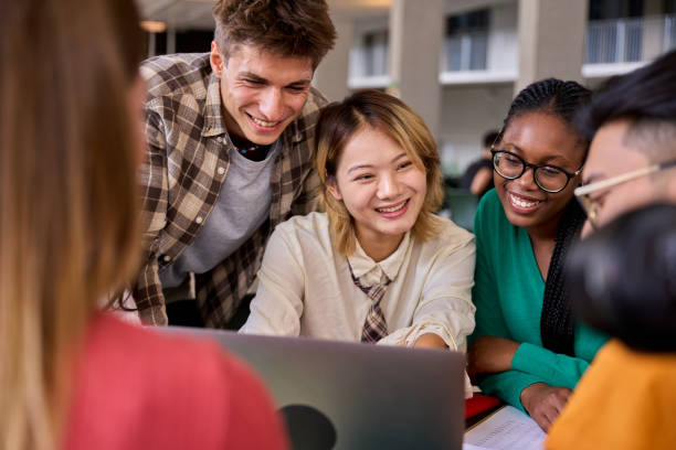 istock Group of diverse smiling young students using laptop gathering sitting in university classroom. 2170103181