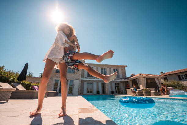 istock Young Girl Playfully Throws Brother into Pool 2170105692