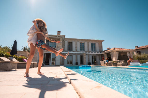 istock Mixed Race Girl Playfully Throws Brother in Pool 2170105704