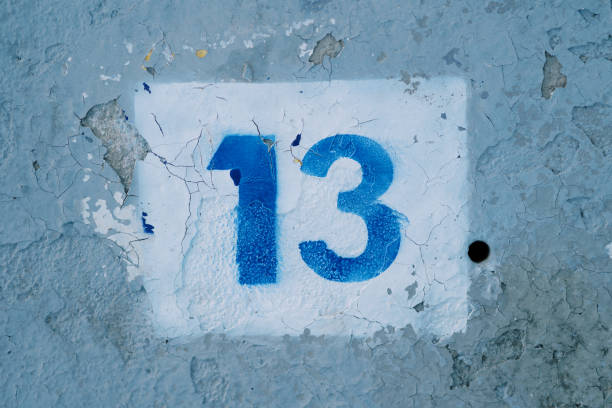 istock Number thirteen drawn in a white rectangle on a blue peeling wall 2170115262