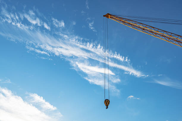 Industrial construction building crane against blue cloudy sky in background