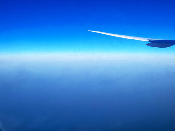 Wing of Airplane Above Cloudy Horizon in Blue Sky