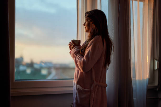 istock Smiling woman day dreaming by the window. 2170125508