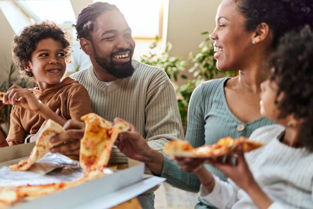 istock Happy black family talking while eating pizza for lunch in dining room. 2170127040