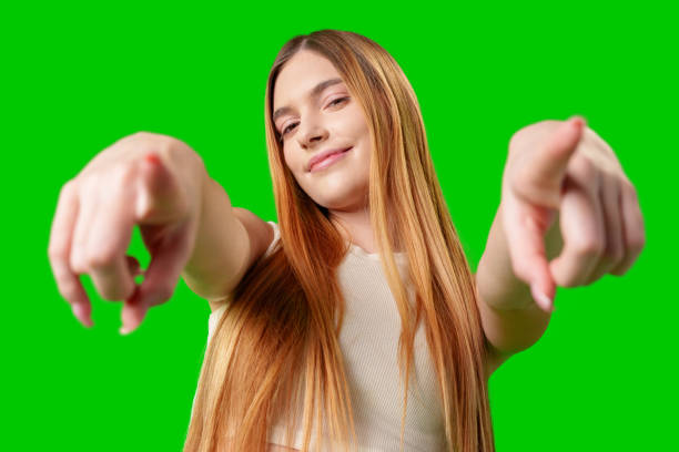 istock Smiling Young Woman Pointing at Camera With Green Screen Background 2170130048