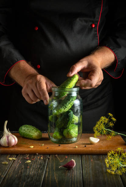 istock Hand filling a jar with cucumbers before canning with garlic and dill on the kitchen table. Concept of pickling cucumbers for long-term storage 2170130440