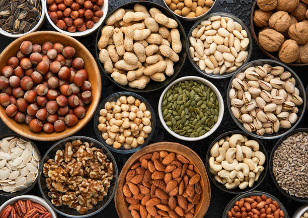 istock Mixed assorted raw healthy nuts and seeds in various bowls on black kitchen background.Peanut,hazelnut,walnut,almonds,pistachio,sunflower,pumpkin,chia and cashew.Top view. 2170130519