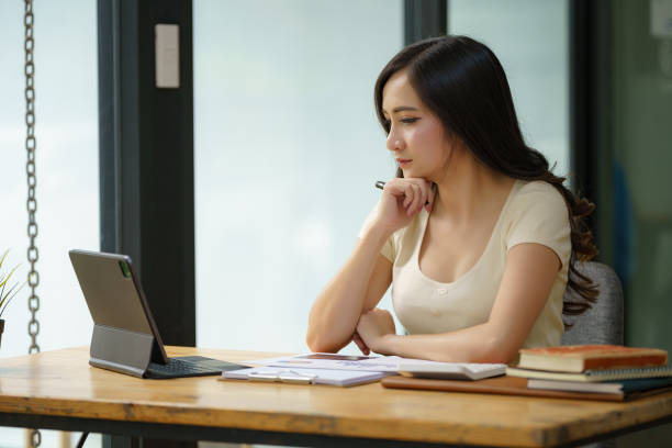 istock Seriously, a young woman working with paperwork and a digital tablet in the office. 2170130527