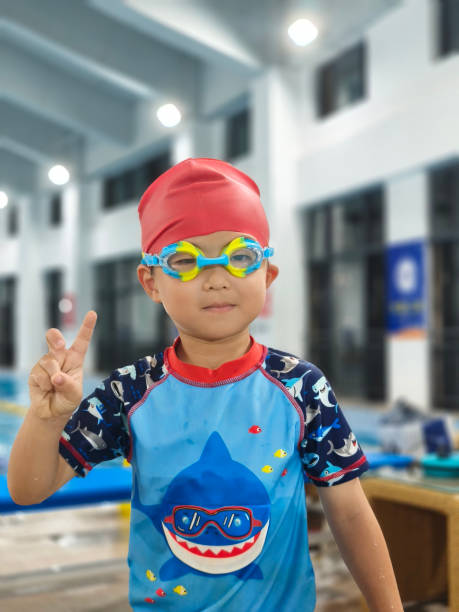 A portrait of a boy standing by the pool ready for class