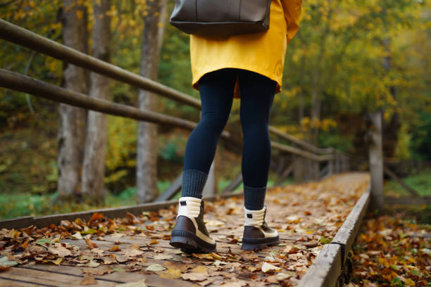 istock A hiker walks along a leaf-covered path in a vibrant autumn forest wearing a bright yellow raincoat and sturdy boots. 2170131206