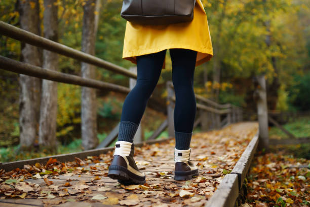 istock A hiker walks along a leaf-covered path in a vibrant autumn forest wearing a bright yellow raincoat and sturdy boots. 2170131209
