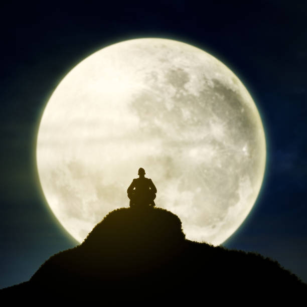 Silhouette a man sitting relaxing under full moon at night