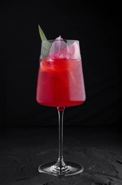istock Red cocktail standing on black surface with flower garnish 2170131719