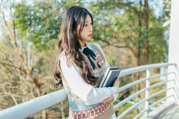 A beautiful student is in the campus hallway, holding a book