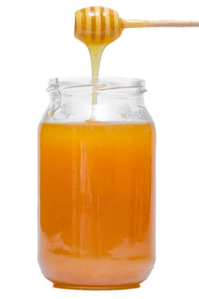 Real honey in a jar flowing down the honeycomb