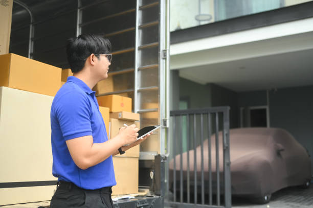 istock Asian male courier worker standing by delivery van and using digital tablet. Shipping and delivery services concept 2170134383